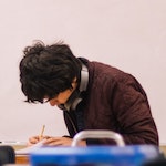 Male instructor grading papers. whiteboard in background