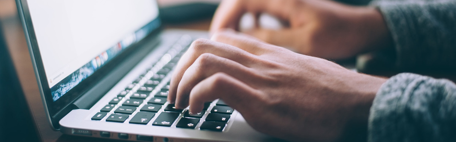 Side view of a person's hands typing on a laptop.